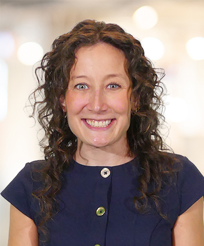 Sydney Habegger Featured Profile | Sydney standing in front of a blurred office hallway